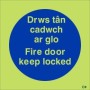 Glow in the dark Fire Door Keep Locked sign in Welsh and English